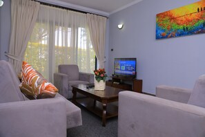 Habitación Deluxe, vista al jardín (Family) | Área de sala de estar | Televisión de pantalla plana