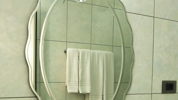 A bathroom with a round mirror, a sink, and a towel rack. - Haile Resort Ziway (Ziway)