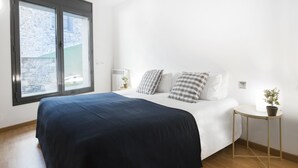 A bedroom with a bed, a bedside table, a lamp, and a window. - Font del Ferro Apartaments (Ransol)