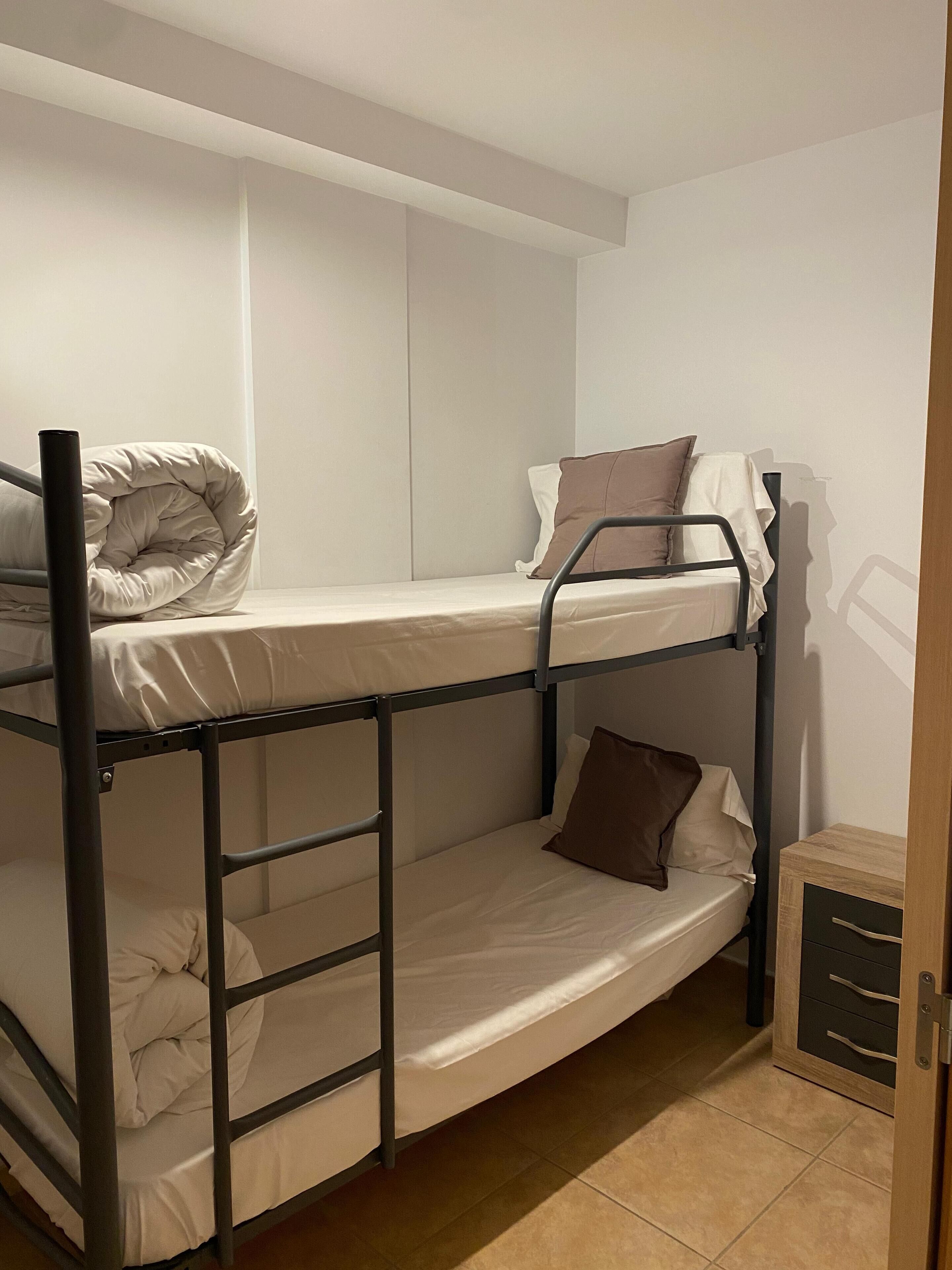 Een slaapkamer met een stapelbed, een houten kast en een deur.