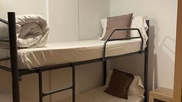 Een slaapkamer met een stapelbed, een houten kast en een deur.