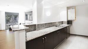 A modern kitchen with granite countertops, dark cabinetry, and a built-in dishwasher. - Font del Ferro Apartaments (Ransol)