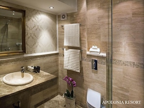 Une salle de bain moderne avec un lavabo en marbre, un grand miroir, une douche en verre et une orchidée en pot.