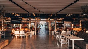 An indoor dining area with tables and chairs, a central walkway, and decorative plants. - Apolonia Resort (Sozopol)