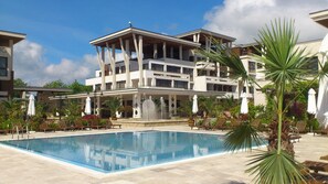 A hotel with a large pool, multiple balconies, and outdoor seating areas. - Apolonia Resort (Sozopol)