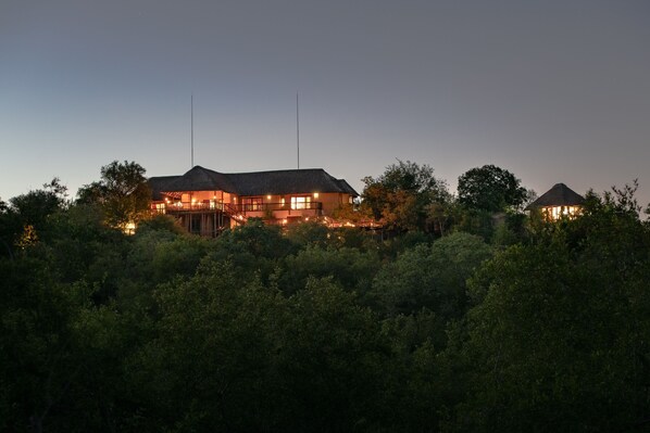A large, multi-story building with a thatched roof, surrounded by dense greenery. - Elephant Game Lodge (Hoedspruit)