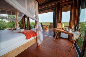 A wooden bed with a white canopy, a table with a kettle, cups, and a sign, and a view of the outdoors. - Elephant Game Lodge (Hoedspruit)