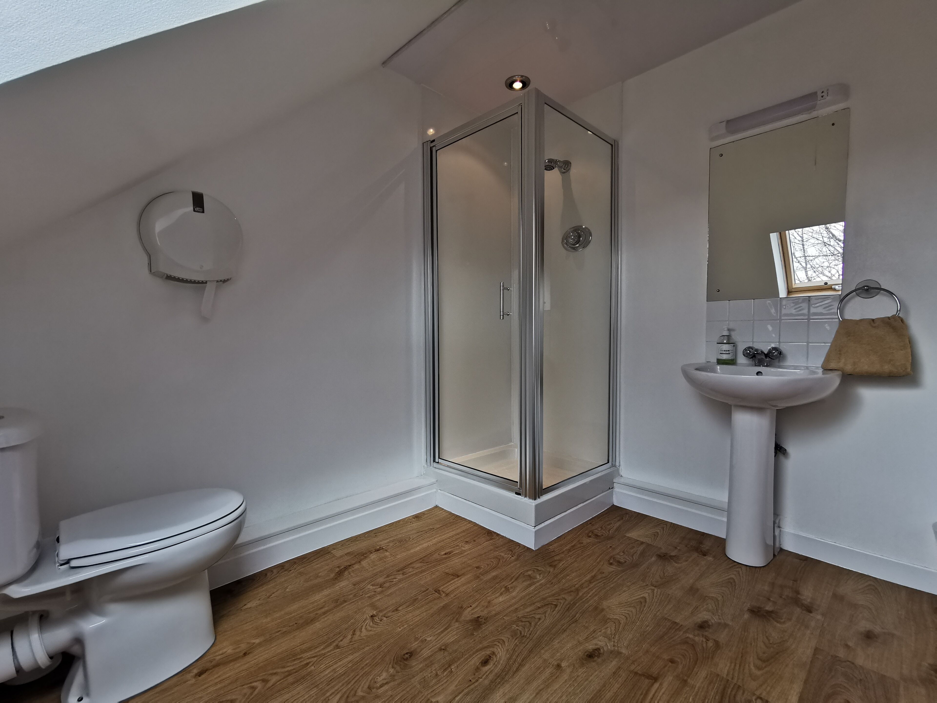 A modern bathroom with a glass-enclosed shower, a white toilet, and a pedestal sink.