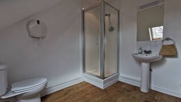 A modern bathroom with a glass-enclosed shower, a white toilet, and a pedestal sink.