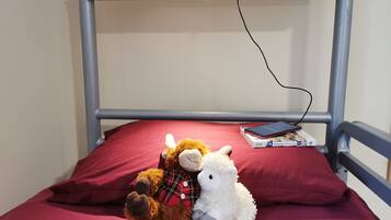 A bunk bed with a red mattress, a stuffed lamb, and a smartphone on the top bunk.