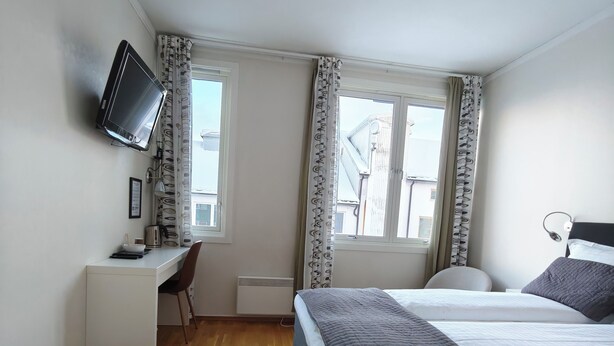 A hotel room with a bed, desk, chair, and a television mounted on the wall. - Gjestehuset Kristiansund (Kristiansund)