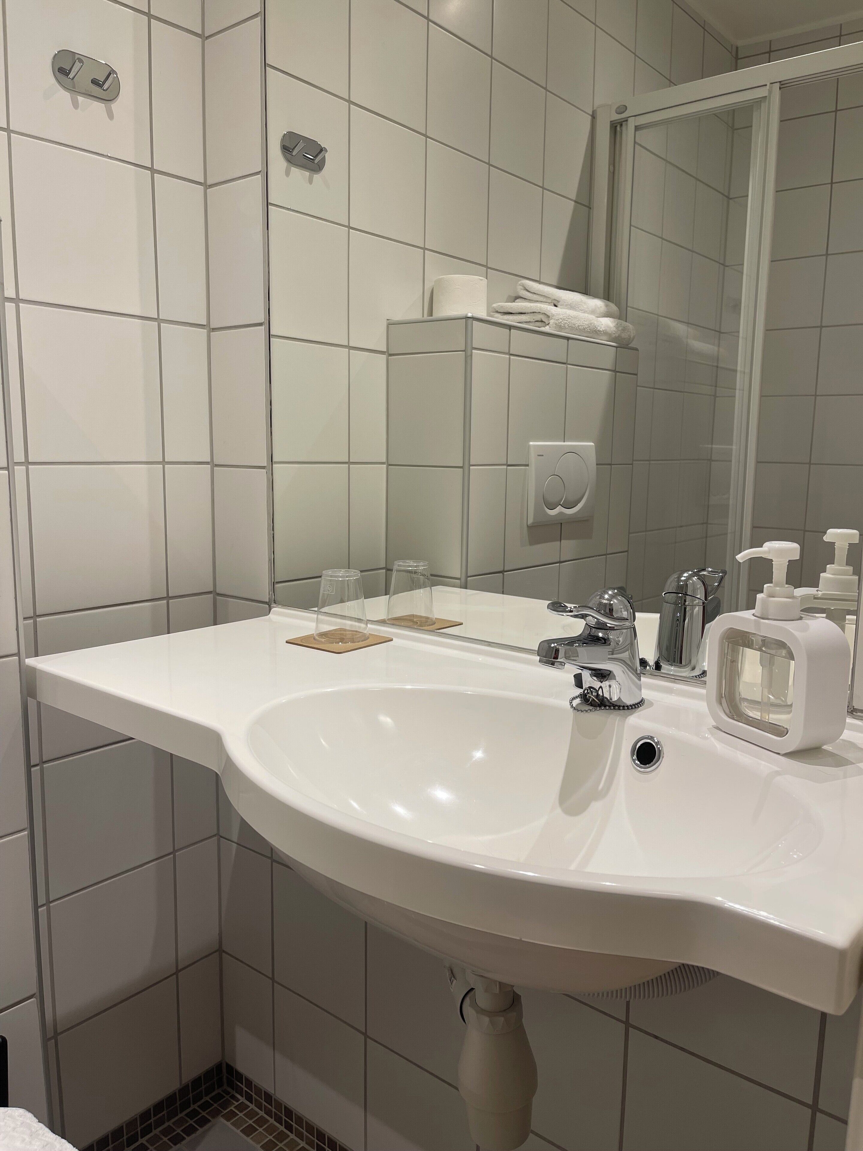 A modern bathroom with a white sink, chrome faucet, and a mirror above it.
