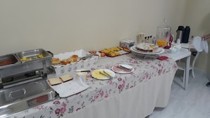 A buffet table with various food items and a cake on a floral tablecloth. - Hotel Interlagos Xua (São Paulo)