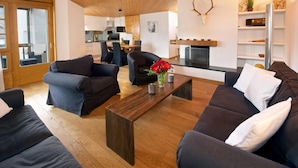 A modern living room with dark sofas, a wooden coffee table, and a fireplace with antlers on the wall.