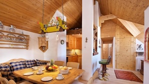 A cozy wooden interior with a dining area, a kitchen, and a living space.