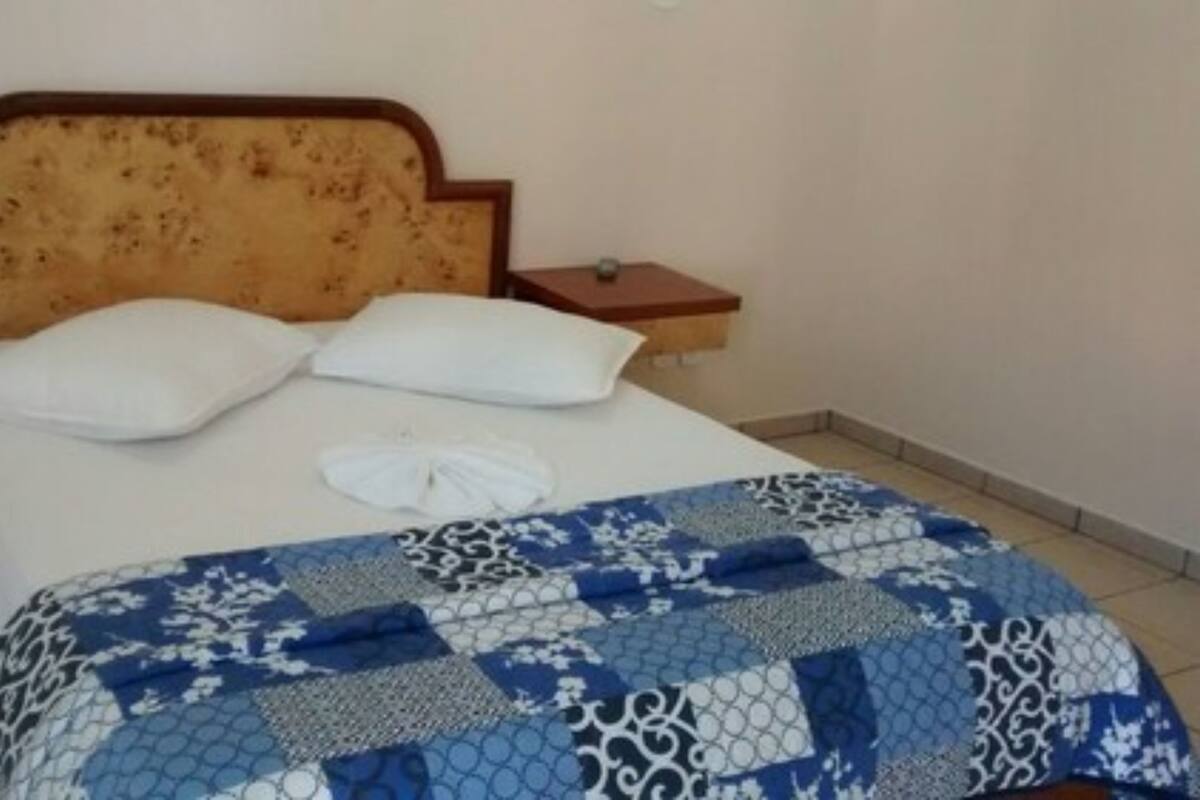 Un lit avec une tête de lit à motifs floraux, deux oreillers blancs et une couvre-lit à rayures bleues et blanches.
