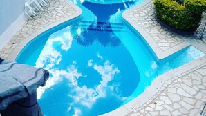 Una piscina con borde de losas de piedra y solárium empedrado.