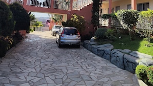 Un edificio de varios pisos con un patio empedrado de piedra, balcones y un coche estacionado.