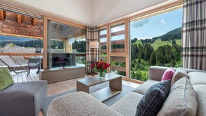 A spacious living area with a large window, a sofa, a coffee table, and a TV.