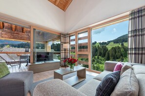 A spacious living area with a large window, a sofa, a coffee table, and a TV. - Turrabuel (Churwalden)