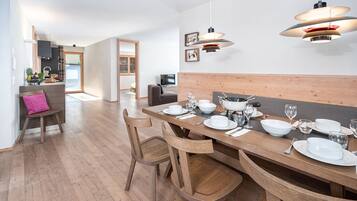 A modern dining area with a wooden table set for four, surrounded by wooden chairs.