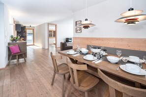 A modern dining area with a wooden table set for four, surrounded by wooden chairs.