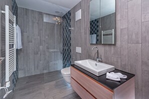 A modern bathroom with a shower, toilet, and vanity with a sink.