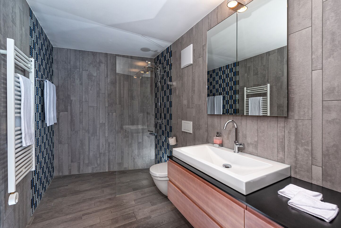 A modern bathroom with a large sink, mirror, and shower.