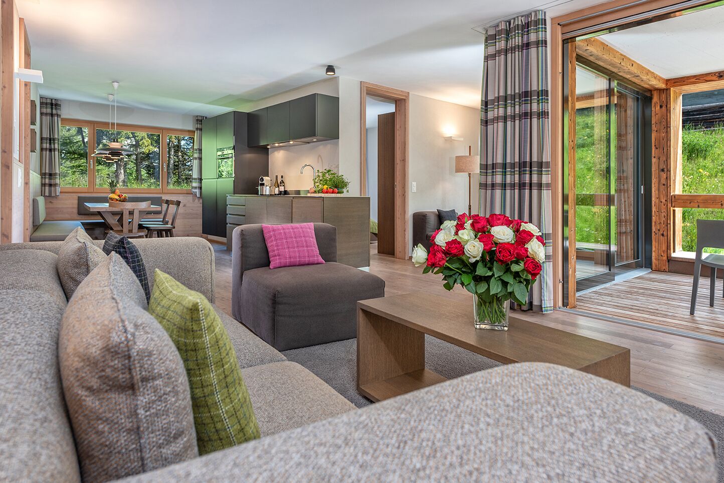Una sala de estar moderna con un sofá, una mesa de centro con un jarrón de flores y vistas a una cocina y comedor.