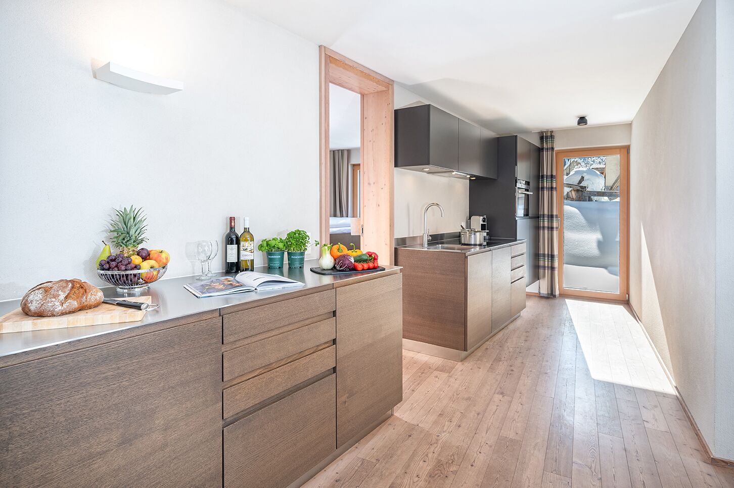 Eine moderne Küche mit Holzausstattung, einer zentralen Kochinsel und Blick ins Freie.