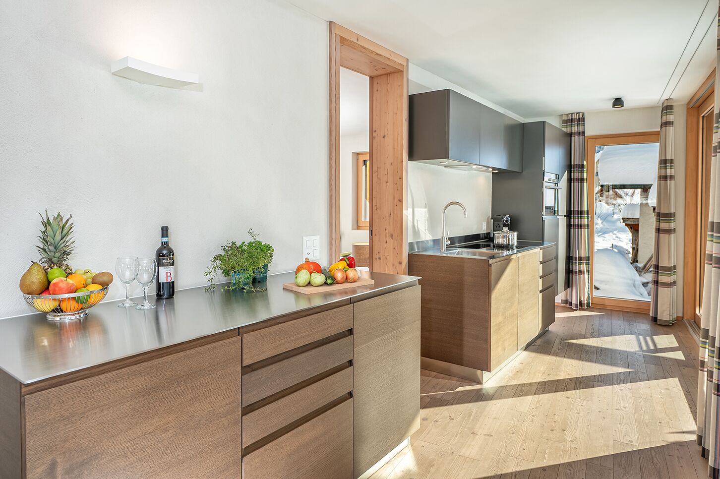 Une cuisine moderne avec un îlot central en bois, un panier de fruits et une bouteille de vin.