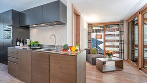 A modern kitchen with a central island, a built-in oven, and a large window. - Turrabuel (Churwalden)