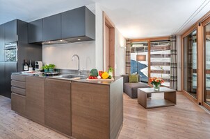 Una cocina moderna con una isla central, horno empotrado y un amplio ventanal.
