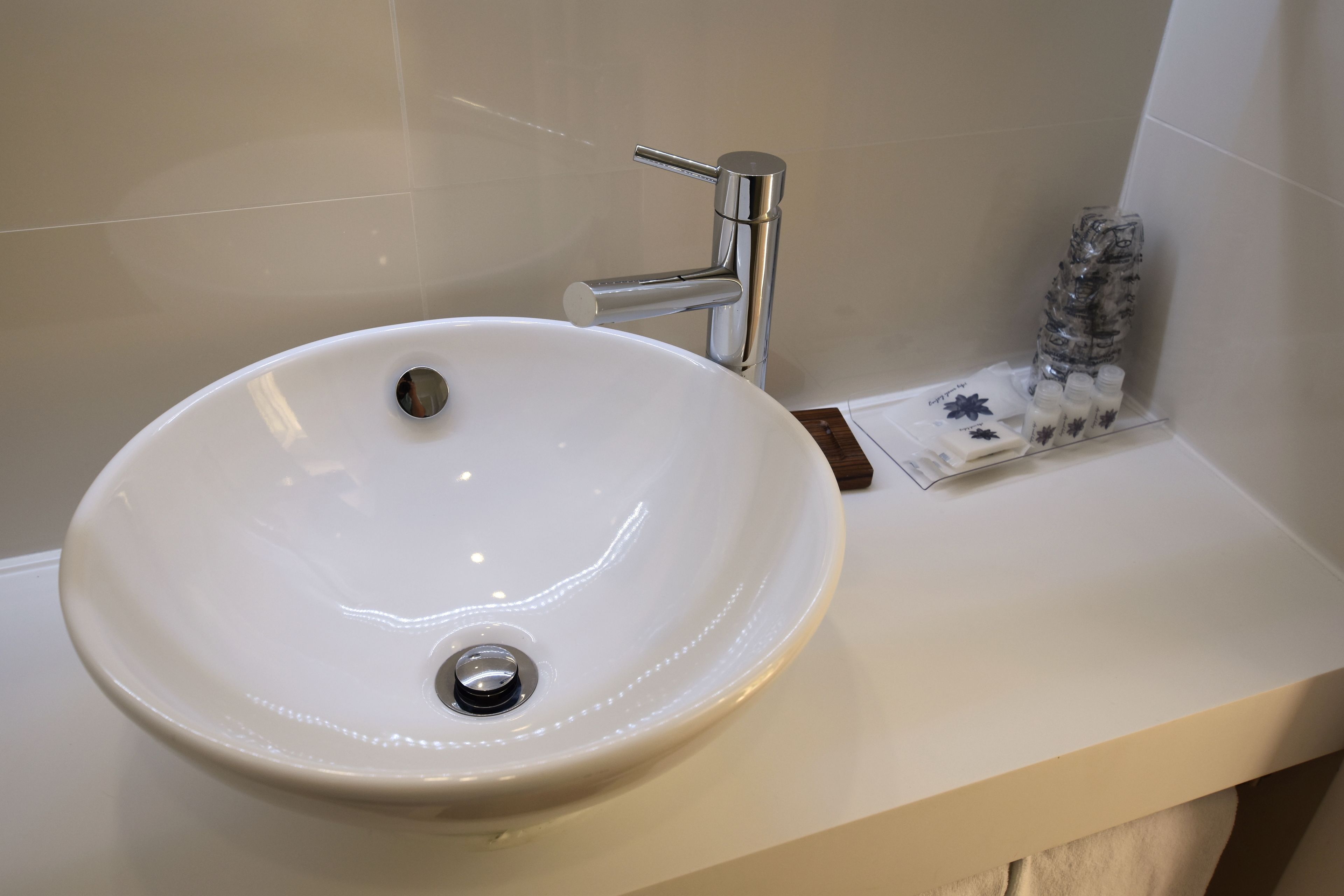 Un lavabo blanco con grifo cromado, una pequeña botella de jabón para manos y una caja de pañuelos en la encimera.