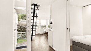 A modern interior with a staircase leading to a balcony, a bed, and a desk area. - Destination Bokenäset (Uddevalla)