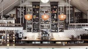A bar area with shelves of liquor bottles, a coffee machine, and hanging glasses. - Destination Bokenäset (Uddevalla)