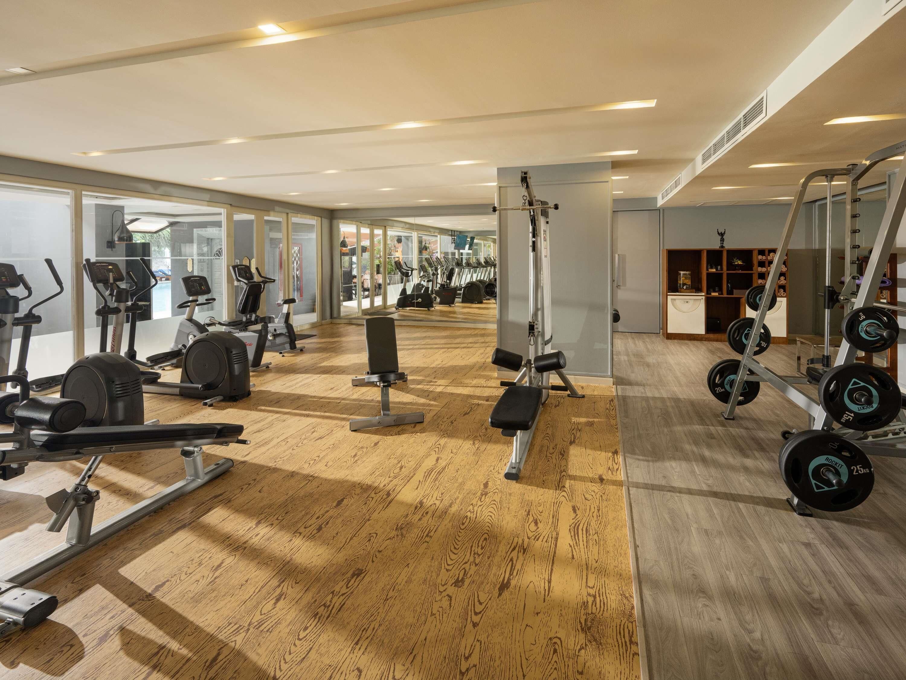 A gym with cardio machines, weightlifting equipment, and a mirrored wall.