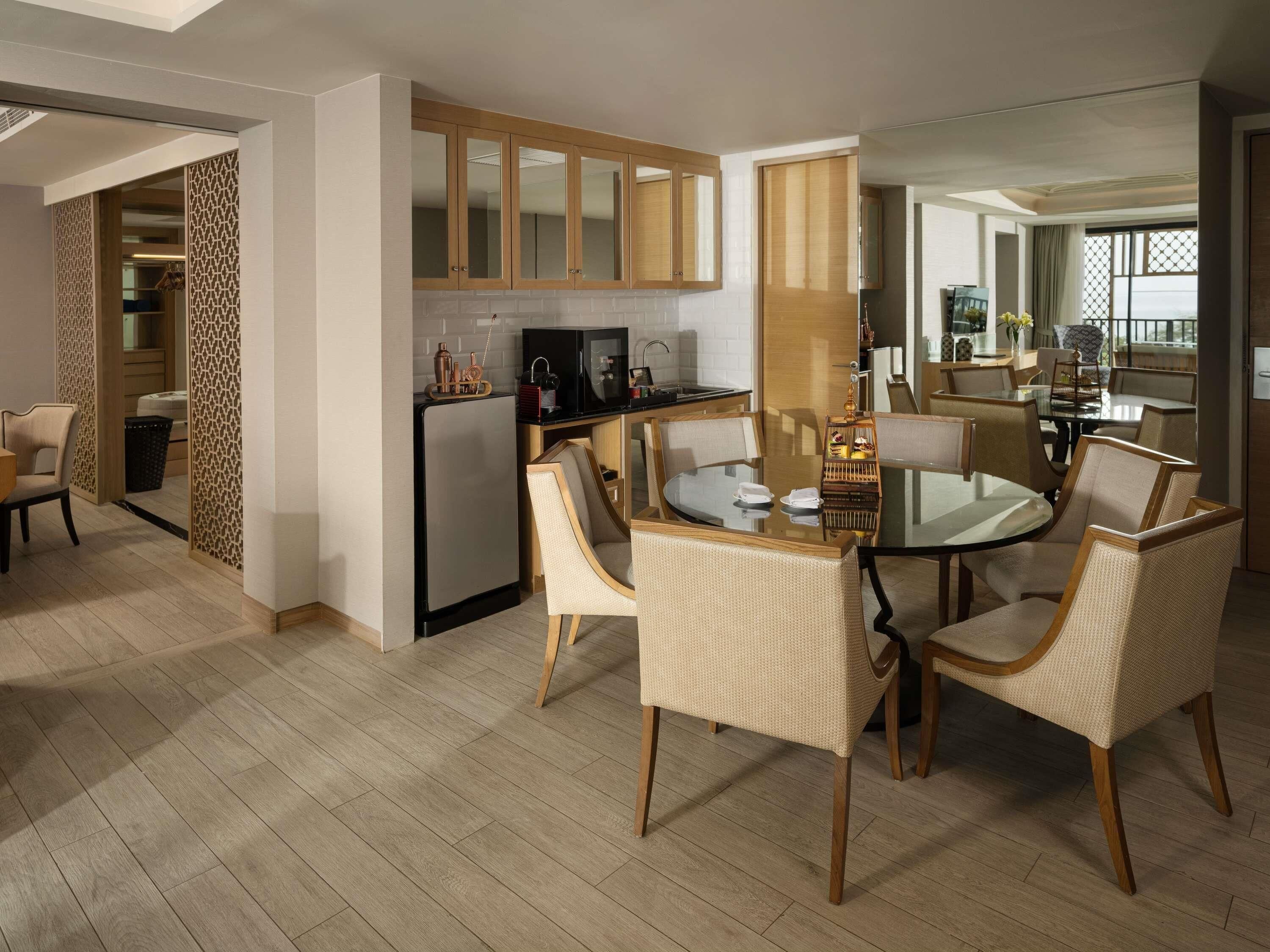 A modern kitchen with a refrigerator, stove, and dining area with wicker chairs and a glass table.