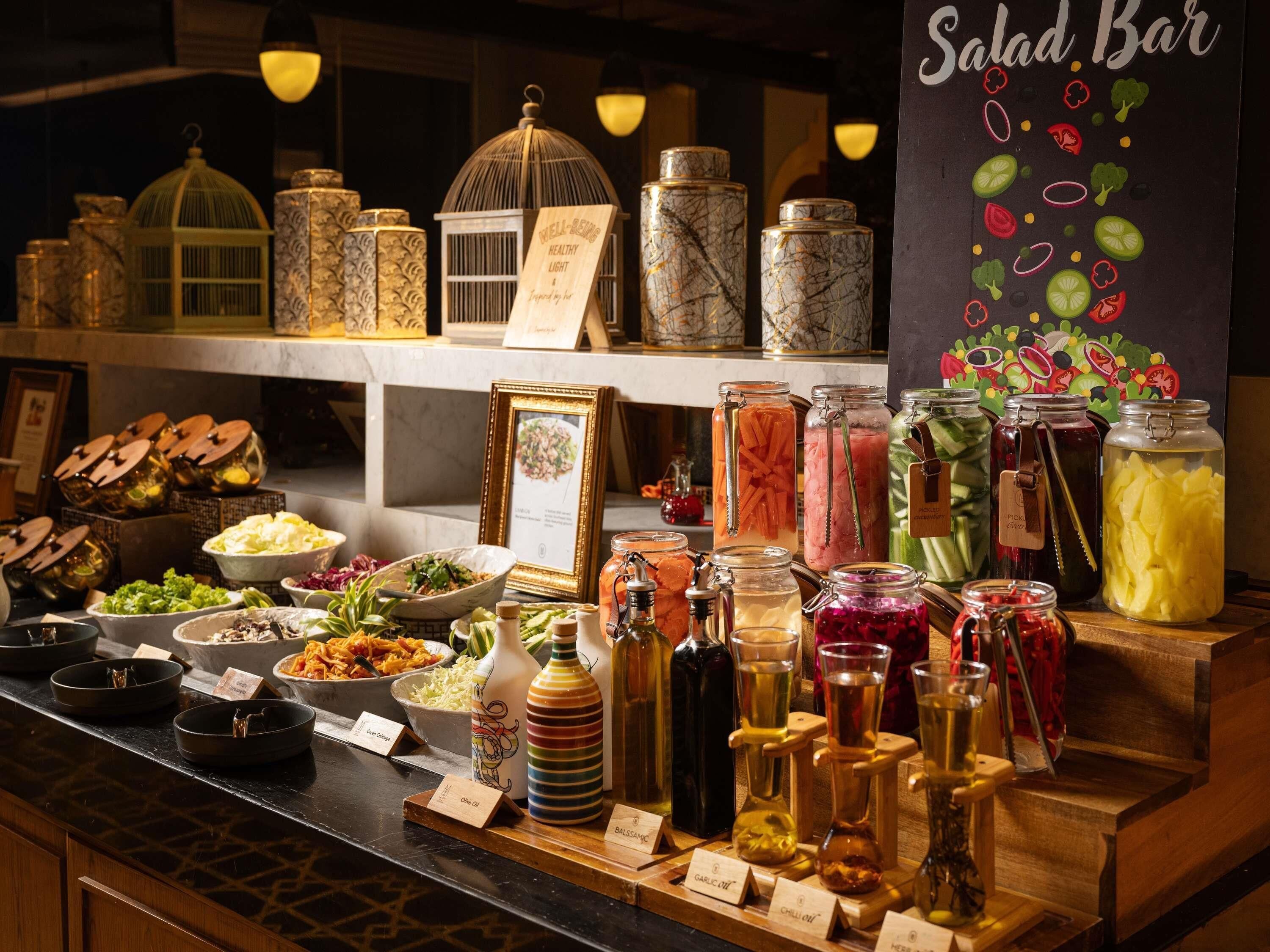 Una barra de ensaladas con botes de verduras encurtidas, salsas y un letrero que dice 'Salad Bar'.
