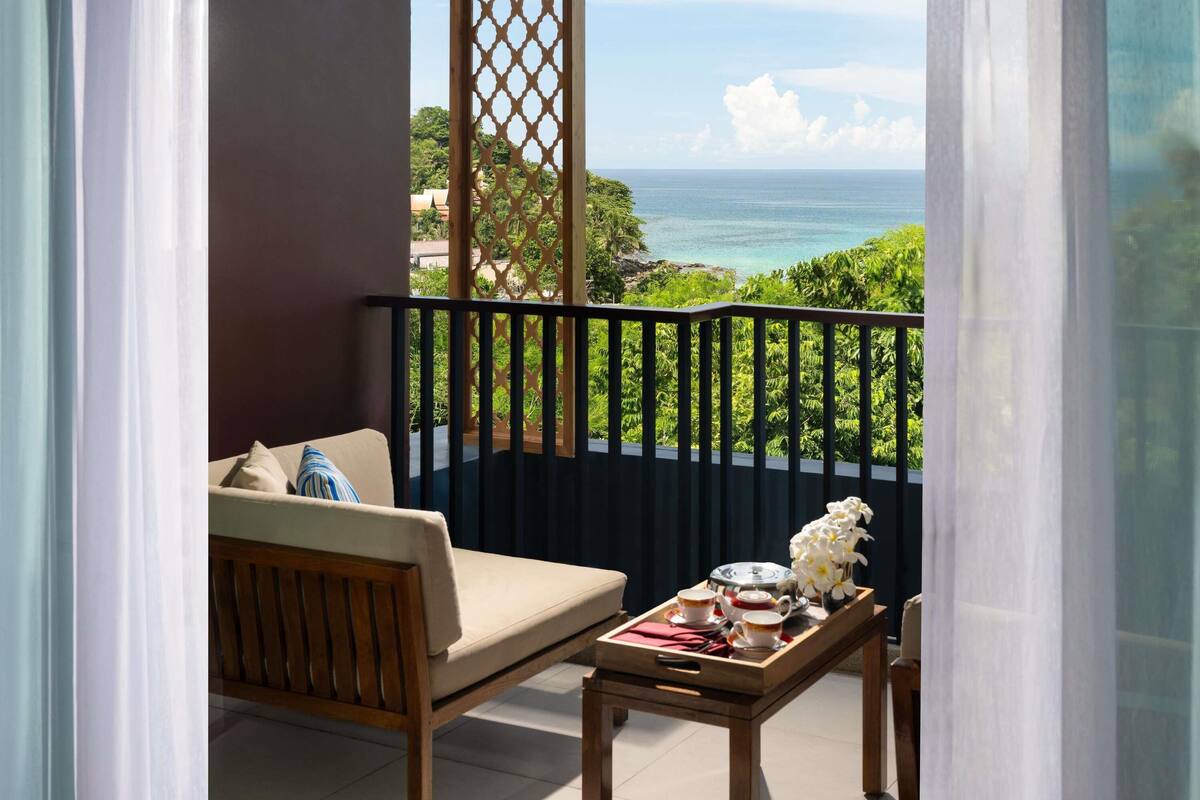 Een balkon met een bank, een tafel met een dienblad en uitzicht op de oceaan.