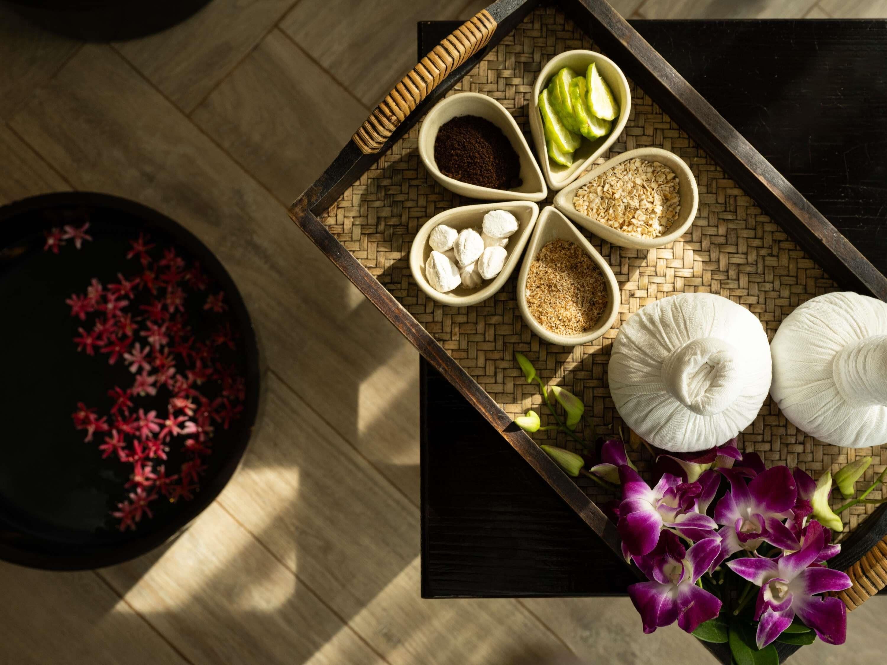 Una bandeja con diversos alimentos y un arreglo floral sobre una mesa de madera.