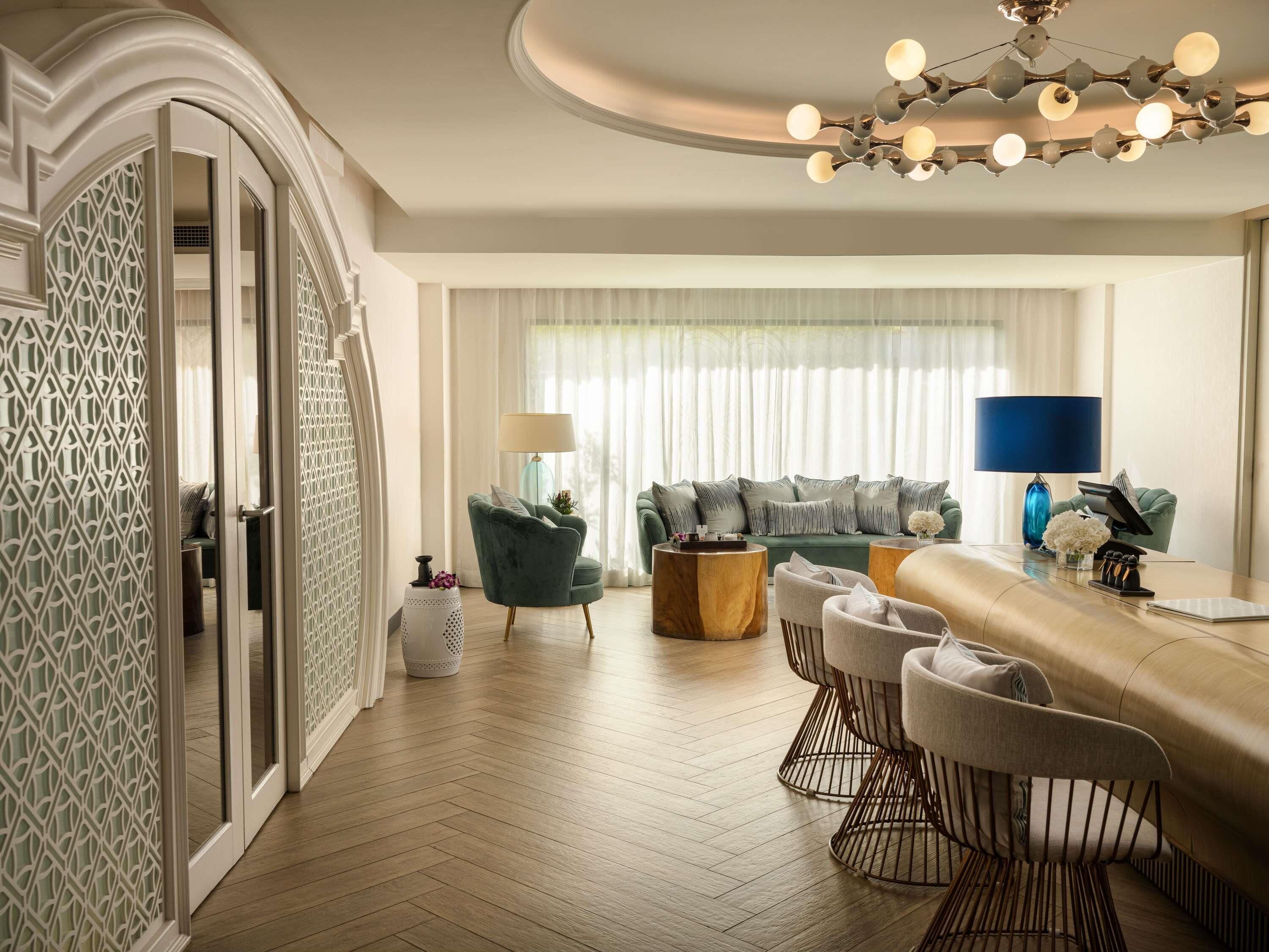A modern living room with a green sofa, a wooden coffee table, and a dining area with bar stools.