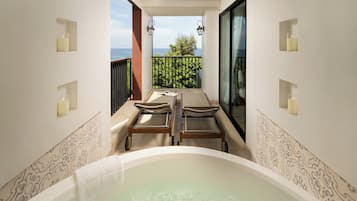 Un área de spa con un jacuzzi, dos tumbonas de madera y vistas al mar.