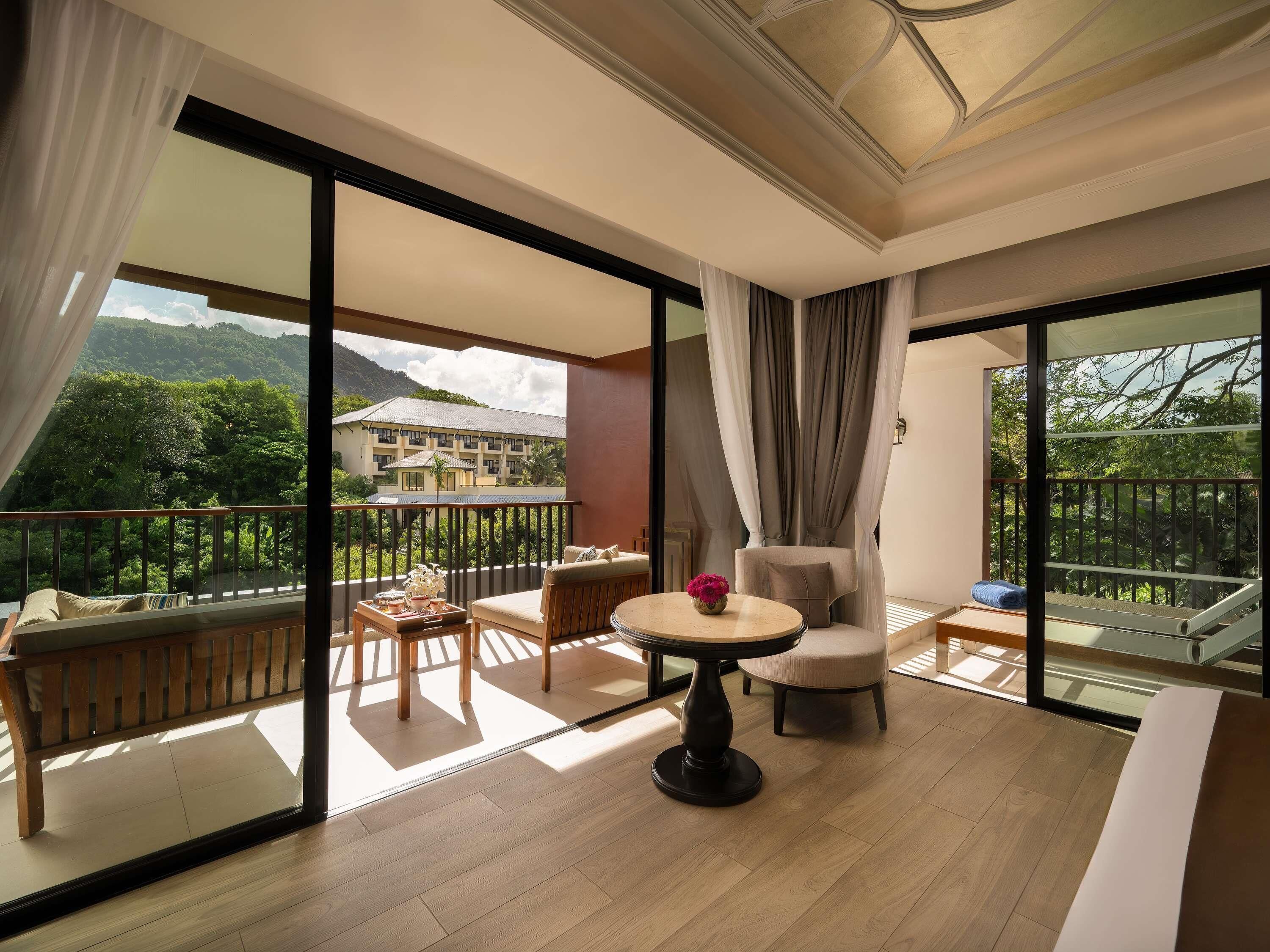 A balcony with a wooden floor, a round table with a vase, and a sofa.