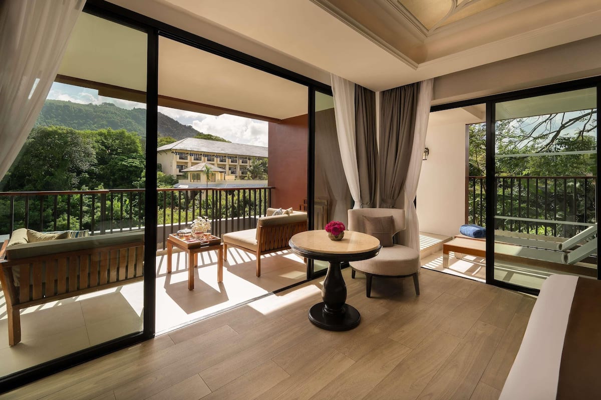 Een balkon met een houten vloer, een ronde tafel met een vaas en een bank.