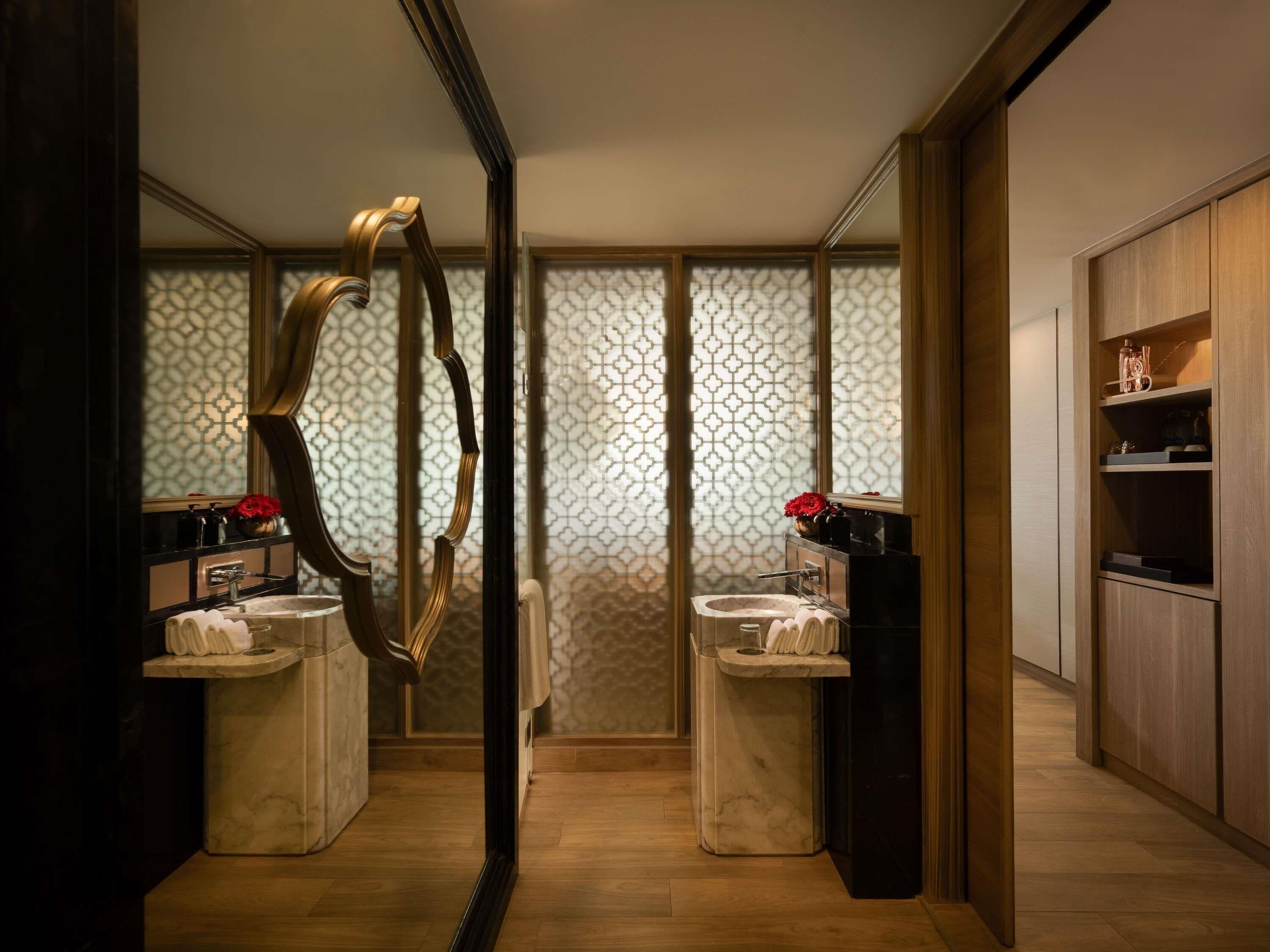 Un baño moderno con dos lavamanos, un espejo grande y un revestimiento de pared con diseño.