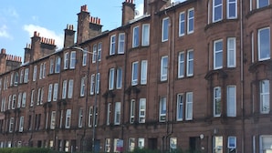 A row of red brick terraced houses with uniform window designs and a clear blue sky.