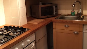 A kitchen with wooden cabinets, a microwave, a gas stove, and a dishwasher.
