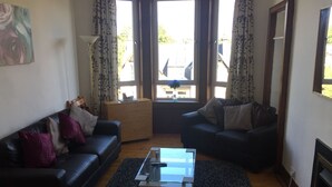 A living room with two sofas, a glass coffee table, and a wooden cabinet.