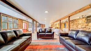Ein geräumiger Flur mit Ledersofas, einer Steinwand und einer Holzbalkendecke.